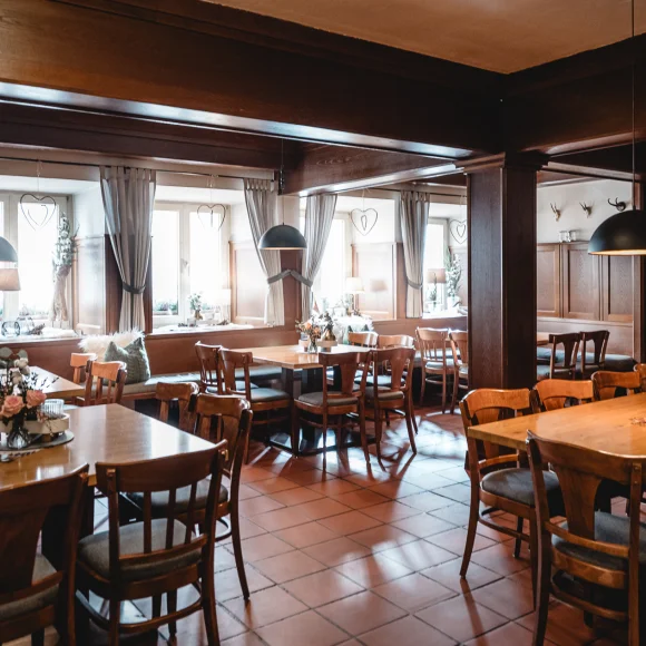 Ein traditionelles Restaurant mit Holzmöbeln, mehreren Tischen und Stühlen, dekoriert mit Blumenarrangements.